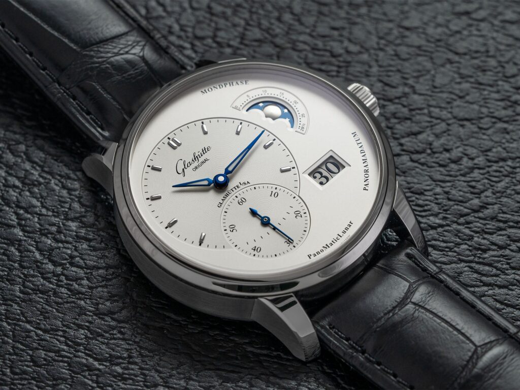 a silver watch with a black leather strap